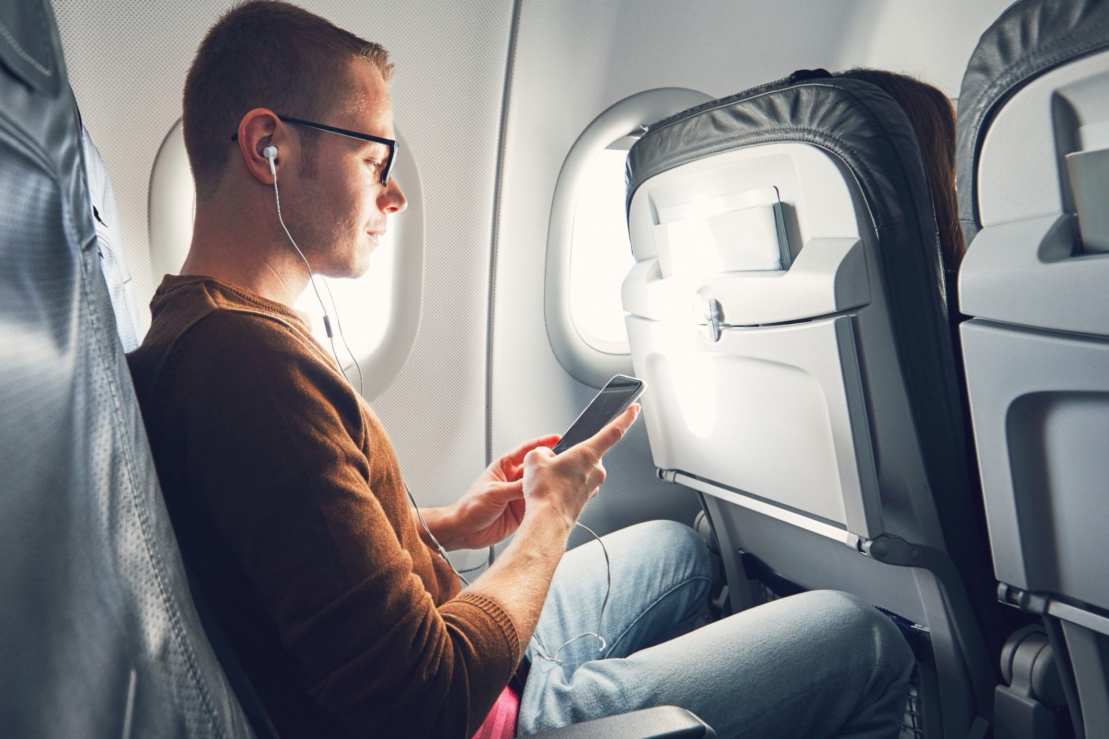 Un homme est assis dans un avion et regarde son téléphone portable.